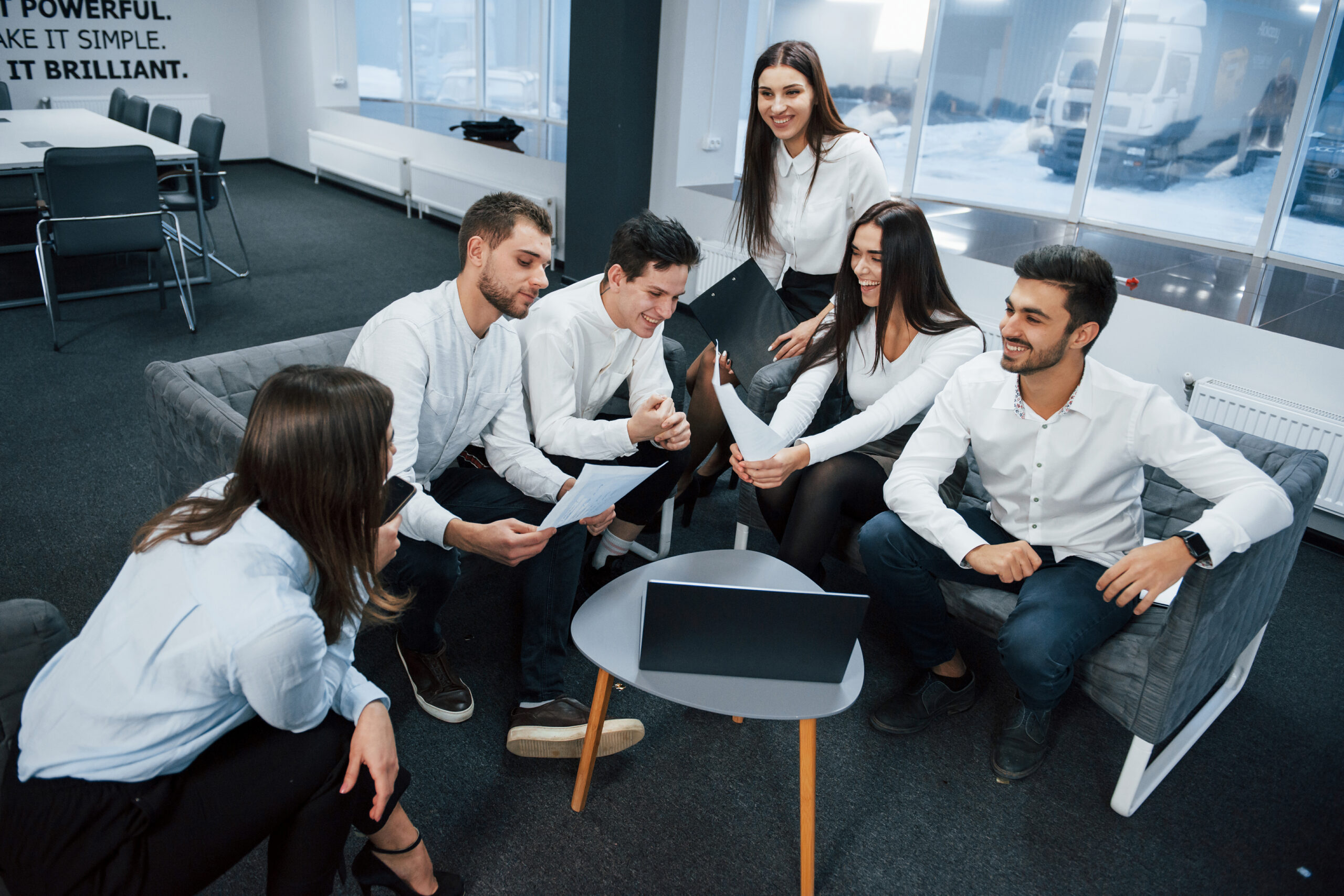 Working together in friendly atmosphere near table with silver colored laptop.